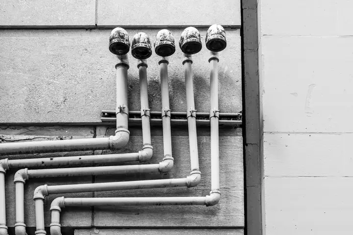 Cañerías de agua sobre un muro, en blanco y negro