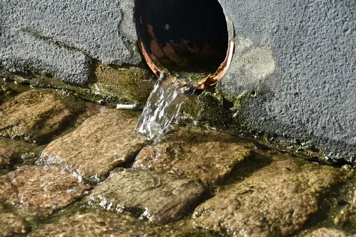 Descarga de agua de una tubería sobre adoquines