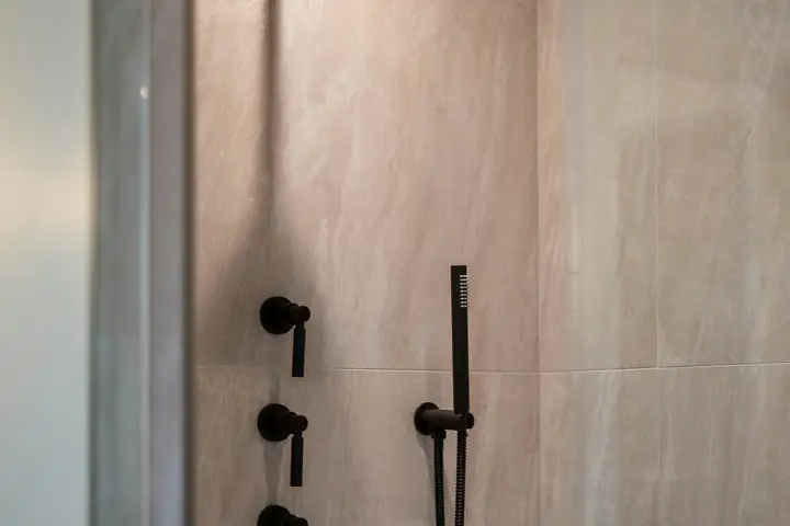 Ducha con grifería negra y muros de porcelanato
