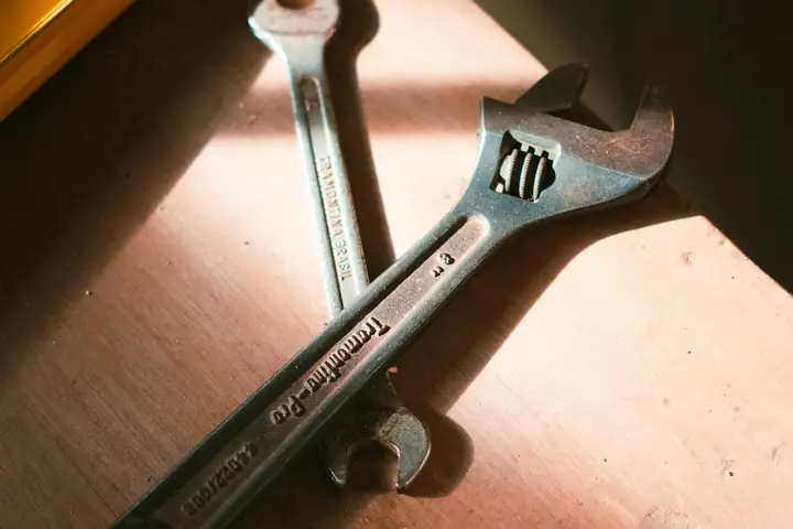 Llaves de gasfíter y nivel sobre una mesa de madera