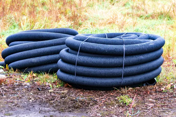 Tubos corrugados de drenaje enrollados en el pasto