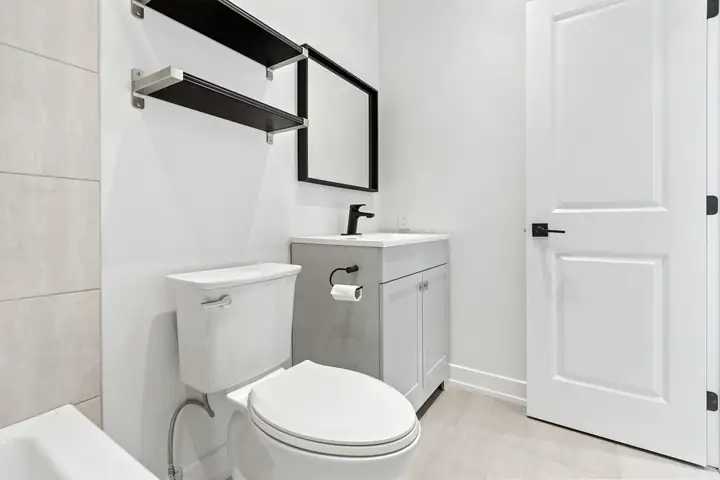 Baño blanco con WC, lavamanos y repisas