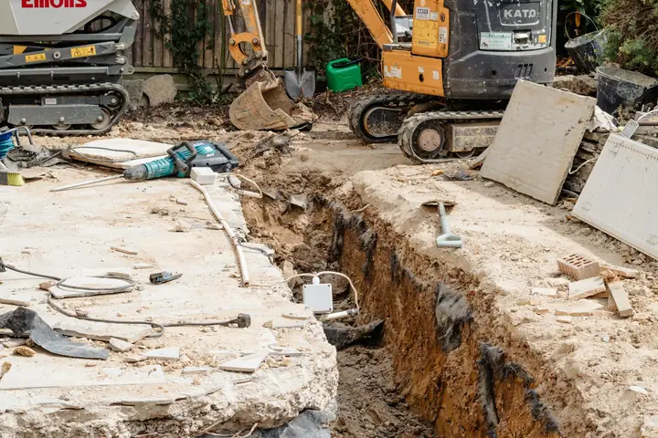 Miniexcavadora abriendo una zanja en un jardín